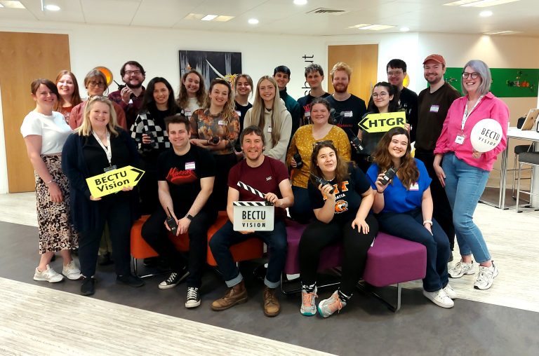 Group of attendees at hit the ground running. One person holds a BECTU Vision clapperboard, two others have yellow BECTU Vision and HTGR arrows
