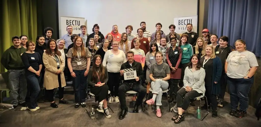 A group photo of participants with one in the centre holding the BECTU Vision clapper board