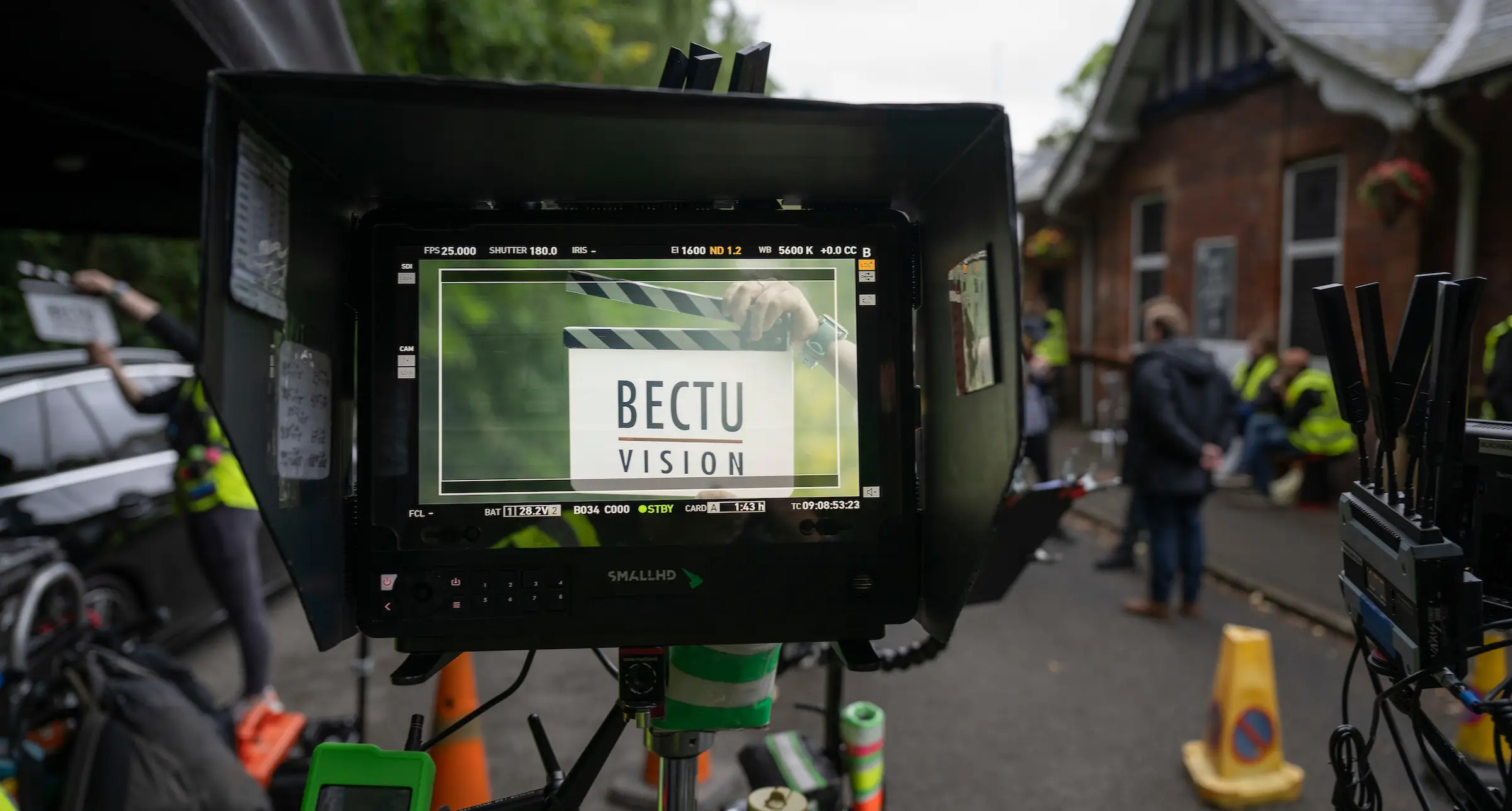 The BECTU Vision clapper board is viewed through a monitor. We can see a camera assistant holding the clapper board in the background.