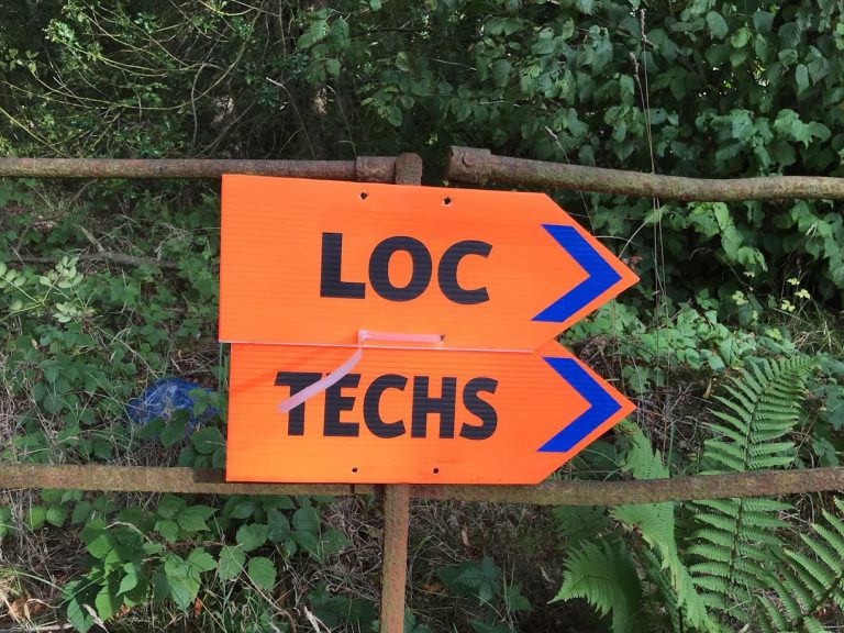Two Film Location Signs Pointing right saying 'Loc' and 'Techs'.