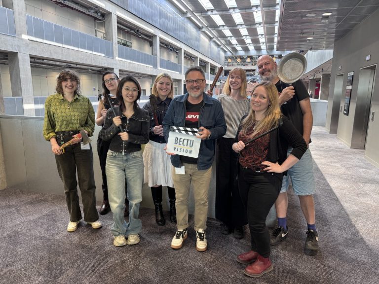A group photo of people standing together and smiling whilst holding film set props who attended the Early Entrant Pathways course for Art Department
